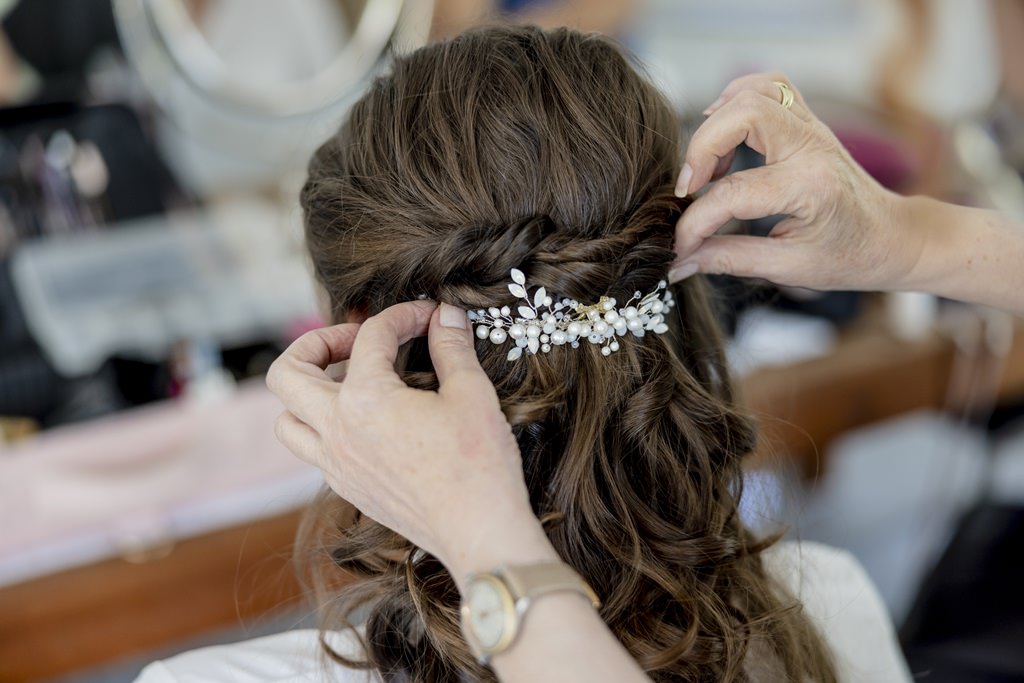 die Stylistin befestigt beim Getting Ready den Haarschmuck der Braut | Hochzeitsfoto: Hanna Witte