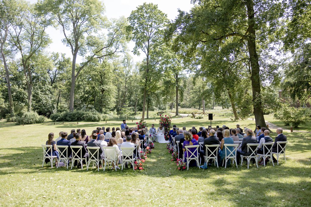 Brautpaar und Gäste während der outdoor Trauung auf der Wiese von Rittergut Orr | Hochzeitsfoto: Hanna Witte