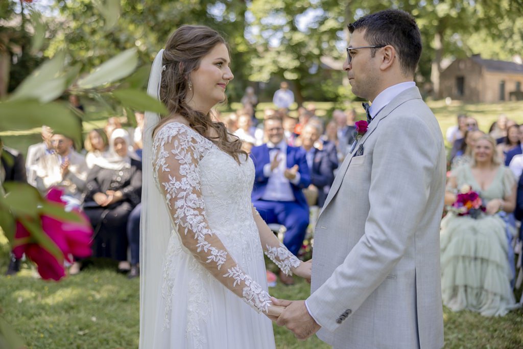 das Brautpaar steht sich beim Ja Wort während der Freien Trauung Hand in Hand gegenüber | Hochzeitsfoto: Hanna Witte