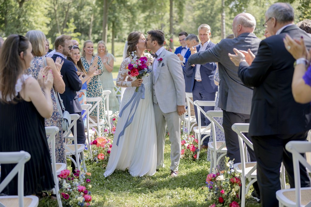 das Brautpaar küsst sich beim Auszug nach der Freien Trauung | Hochzeitsfoto: Hanna Witte