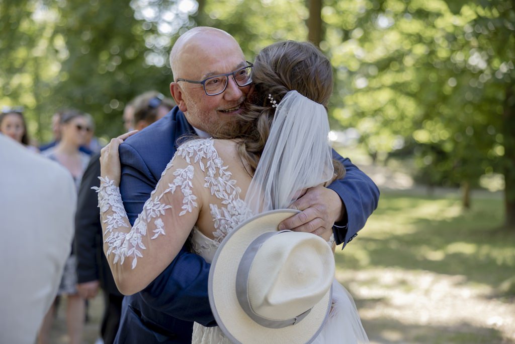 die Braut wird von einem männlichen Gast nach der Trauung umarmt | Hochzeitsfoto: Hanna Witte