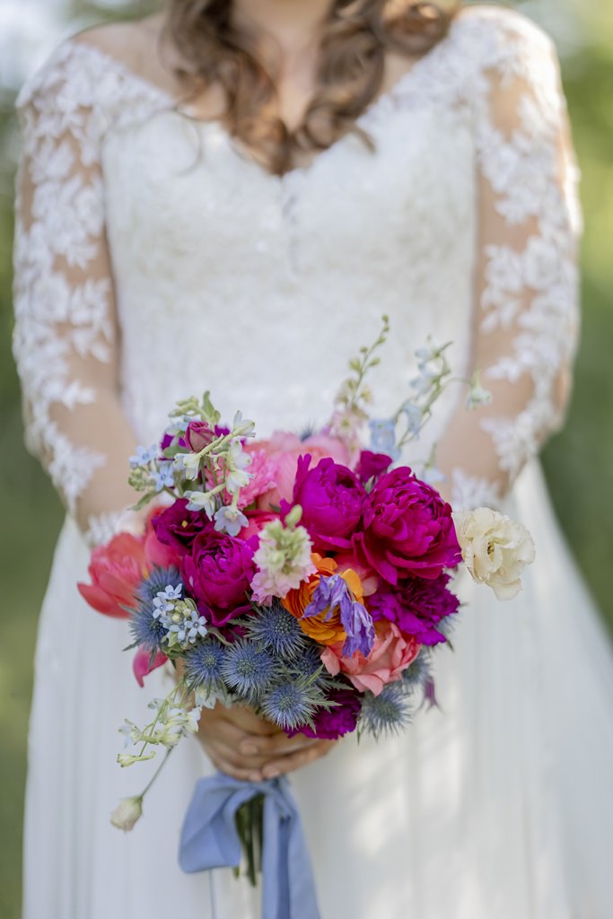 farbenfroher Brautstrauß mit Pfingstrosen, Disteln, Rosen und Rittersporn in pink, blau, rosa und orange | Hochzeitsfoto: Hanna Witte