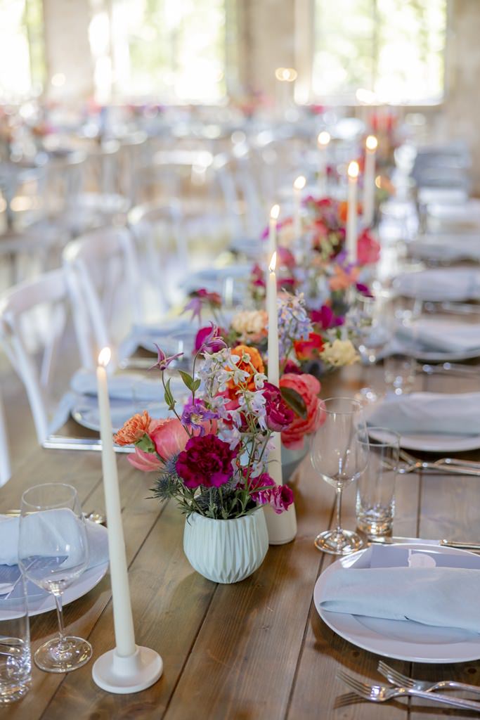 Hochzeits-Tischdeko mit Stabkerzen und bunten Blumen in vielen kleinen Vasen | Hochzeitsfoto: Hanna Witte